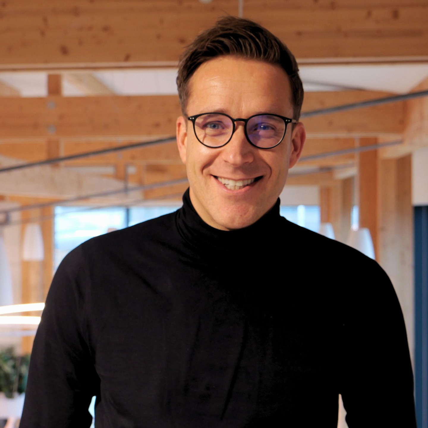 GP JOULE Mitarbeiter mit dunklem Pullover in modernem Büro.